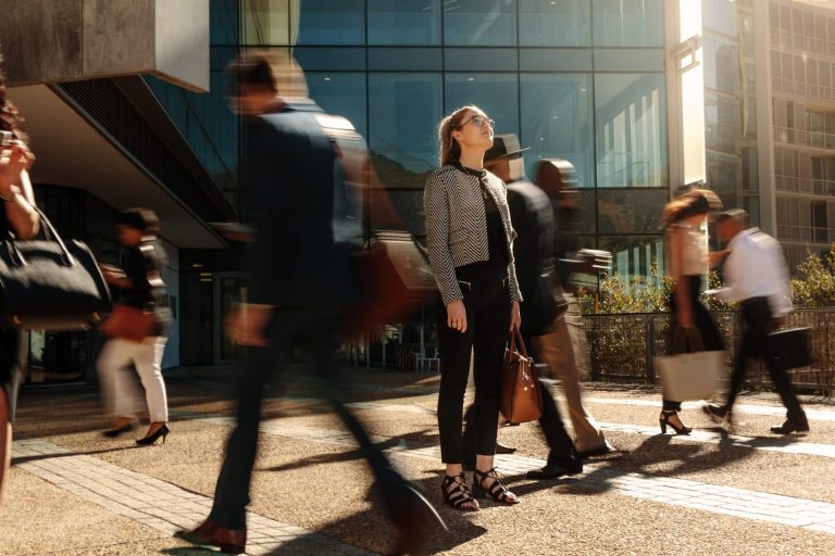 business women standing in the middle of a rushing busy crowd symbolizing the rush of corporate travel